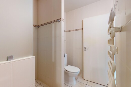 salle de bains avec inside property, mur en carrelage, tile wall, toilette, et sol en carrelage