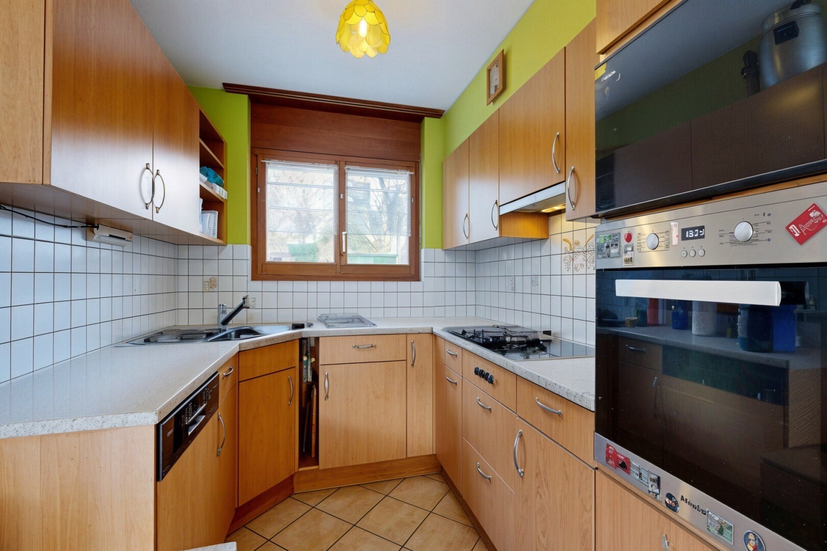 cuisine avec four, light countertops, plans de travail, light floor, et tile floor