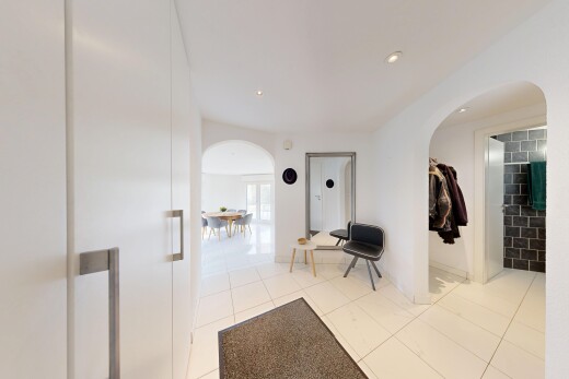 corridor featuring arched walkways, light tile patterned floors, and recessed lighting