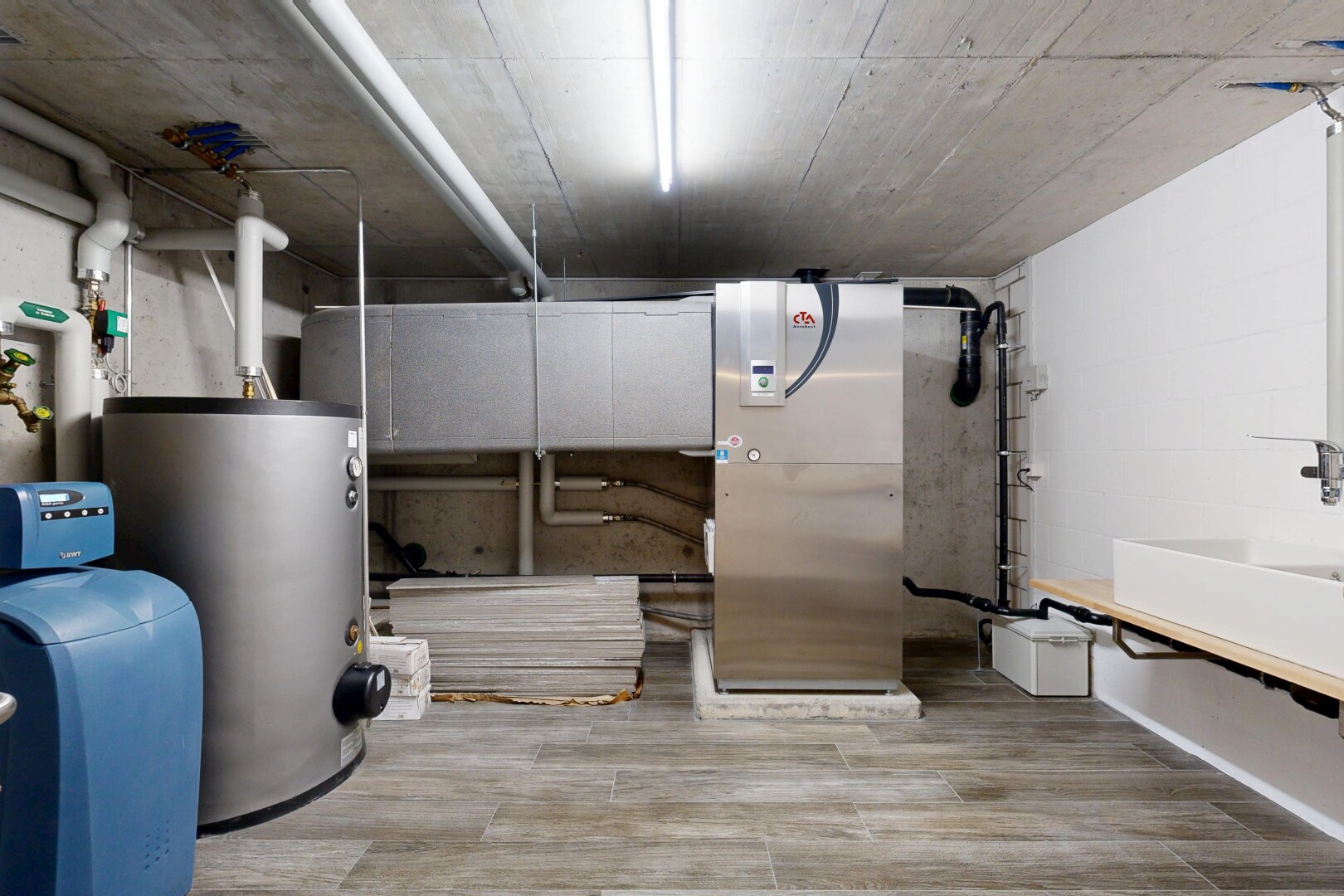 espace intérieur avec concrete ceiling, inside community, chauffe-eau, lavabo (ou coiffeuse selon le contexte), et wood finish floor