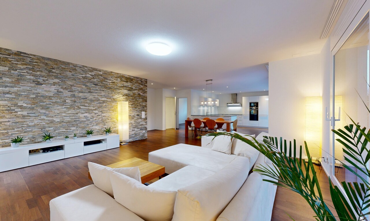 salon / salle à manger avec mur en pierre, stone wall, inside property, sol en finition bois, et wood finish floor