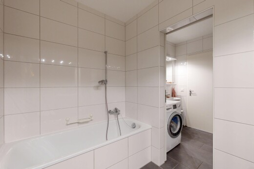 salle de bains avec salle de bain complète, lave-linge et sèche-linge, dark floor, mur en carrelage, et tile wall