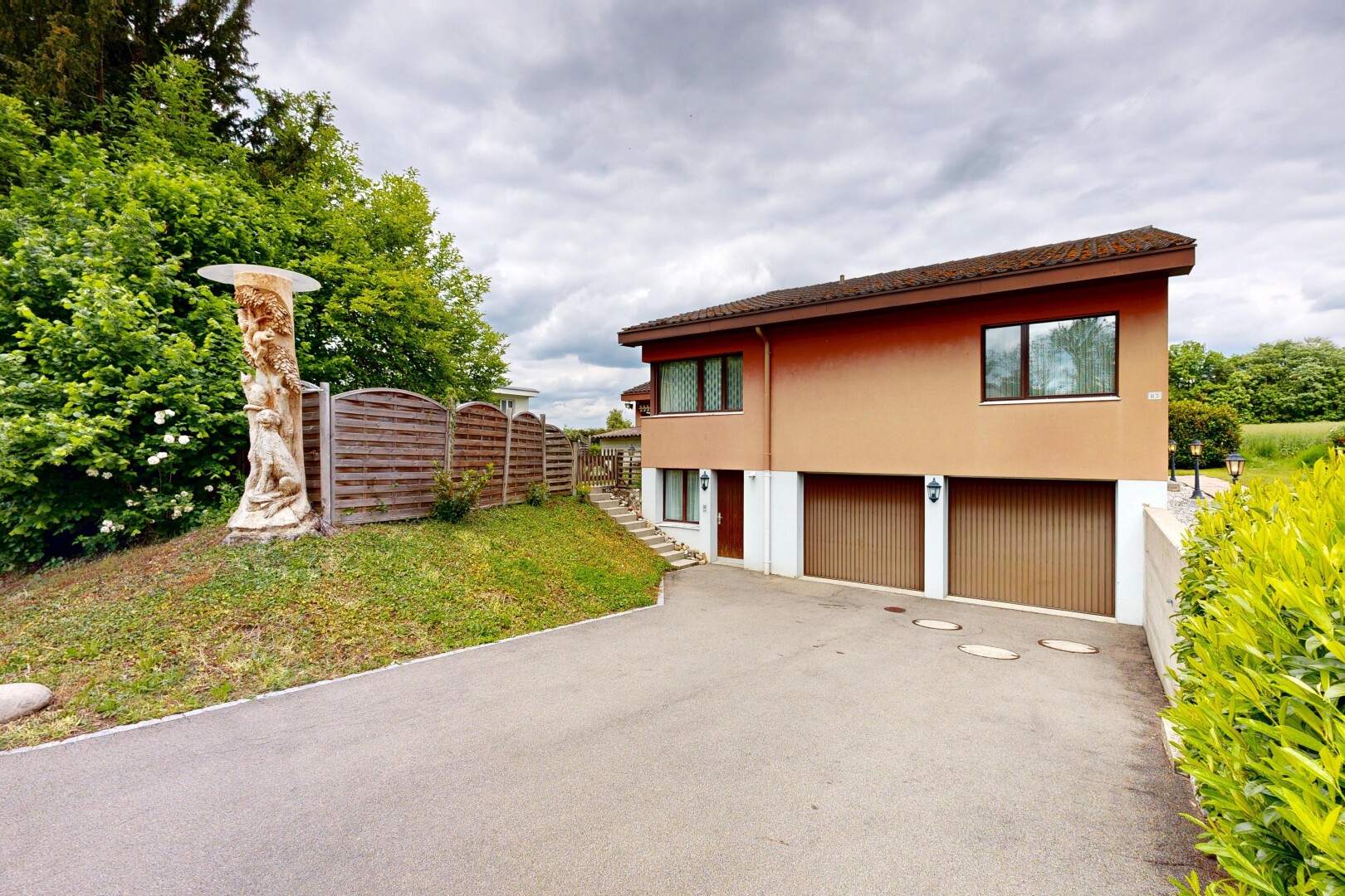 außenansicht mit overcast, eingebaute garage, auffahrt, rasen, und zaun