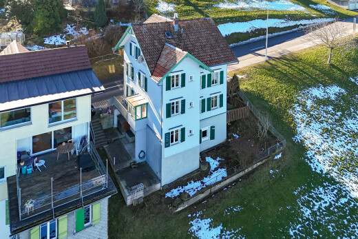 façade avec drone view, terrasse, toit en métal, bardage en stuc, et vue sur l'eau