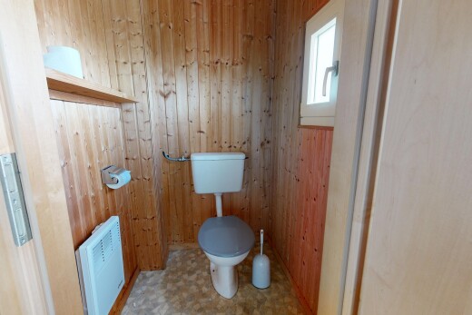 salle de bains avec toilette, vinyl floor, sol en vinyle, wood wall, et mur en bois