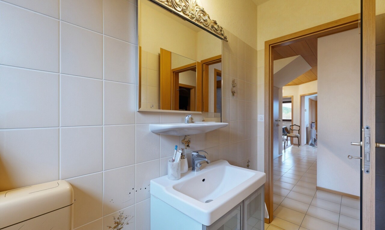 salle de bains avec miroir, toilette, lavabo (ou coiffeuse selon le contexte), mur en carrelage, et tile wall