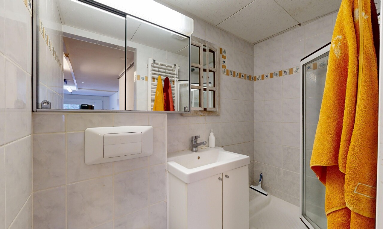 salle de bains avec chauffe-serviettes, salle de bain complète, lavabo (ou coiffeuse selon le contexte), miroir, et douche