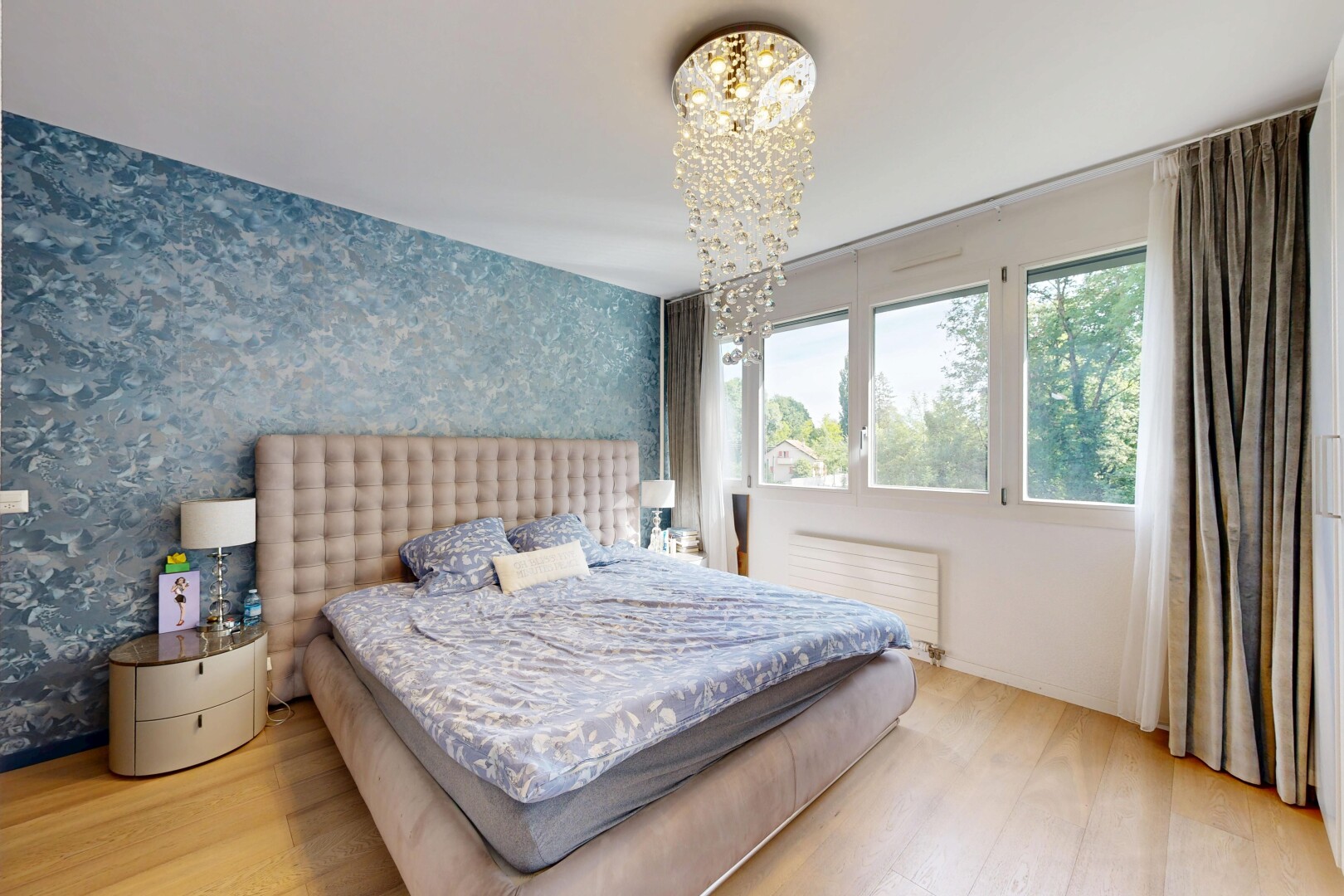 room with light wood-type flooring, a chandelier, radiator, and wallpapered walls