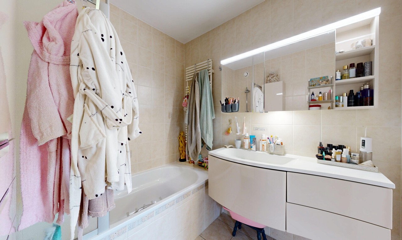 bathroom with vanity, tiled shower / bath, tile walls, and a towel warming rack