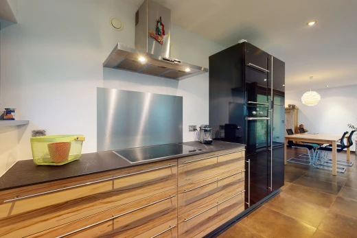 cuisine avec four, réfrigérateur, cuisinière électrique, hotte, suspension, et plan de travail foncé