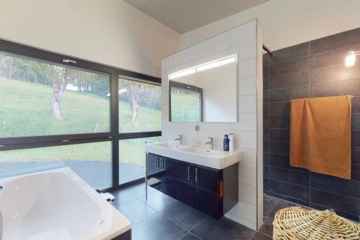 salle de bains avec carrelage, lumière naturelle, baignoire, douche, miroir, meuble-lavabo, et double vasque