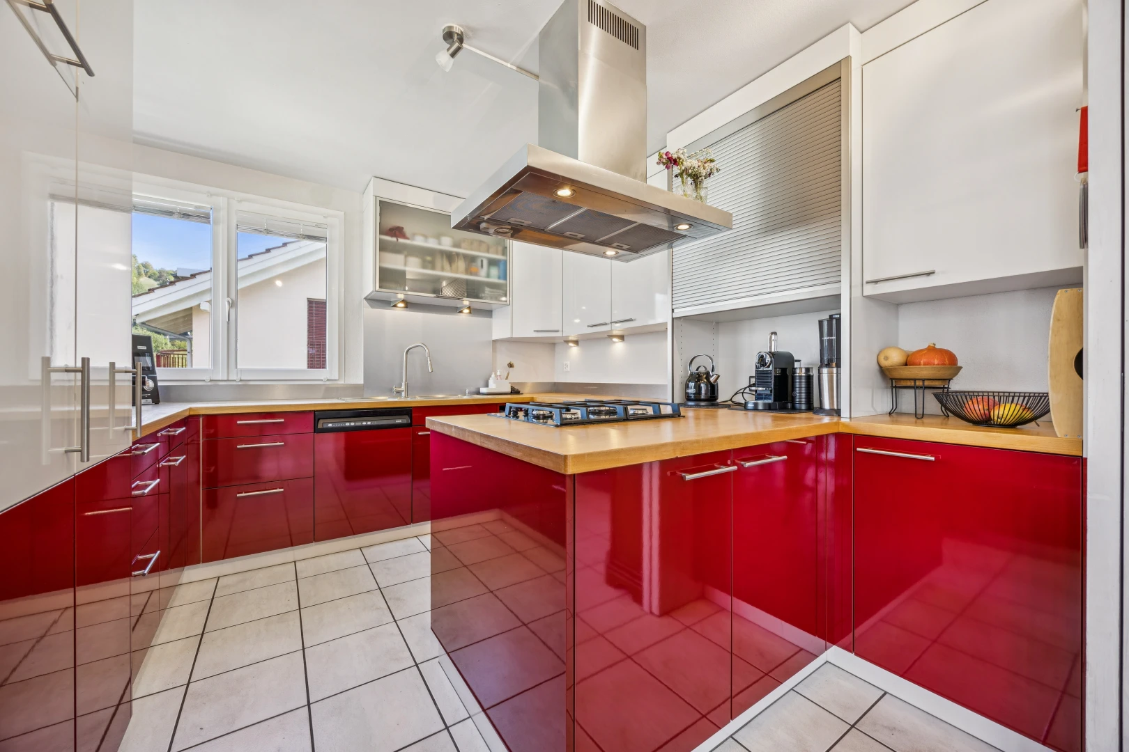 cuisine avec hotte, armoires rouges, red cabinets, light floor, et two tone kitchen