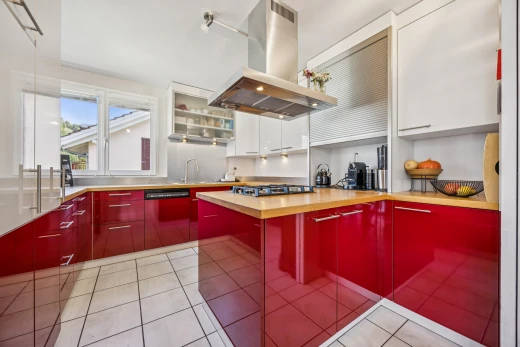 cuisine avec hotte, armoires rouges, red cabinets, light floor, et two tone kitchen