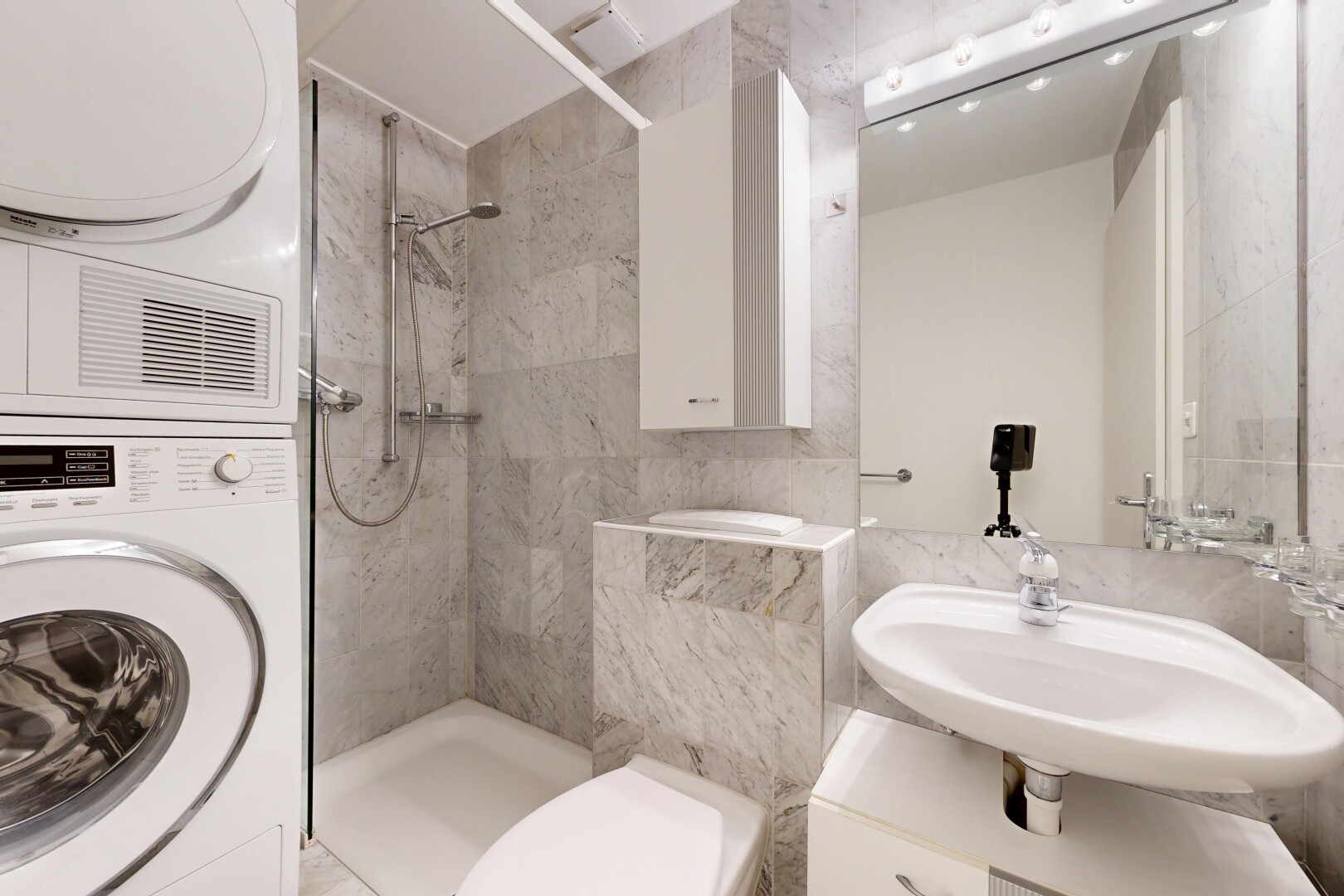 full bathroom featuring a stall shower, tile walls, and stacked washer and clothes dryer