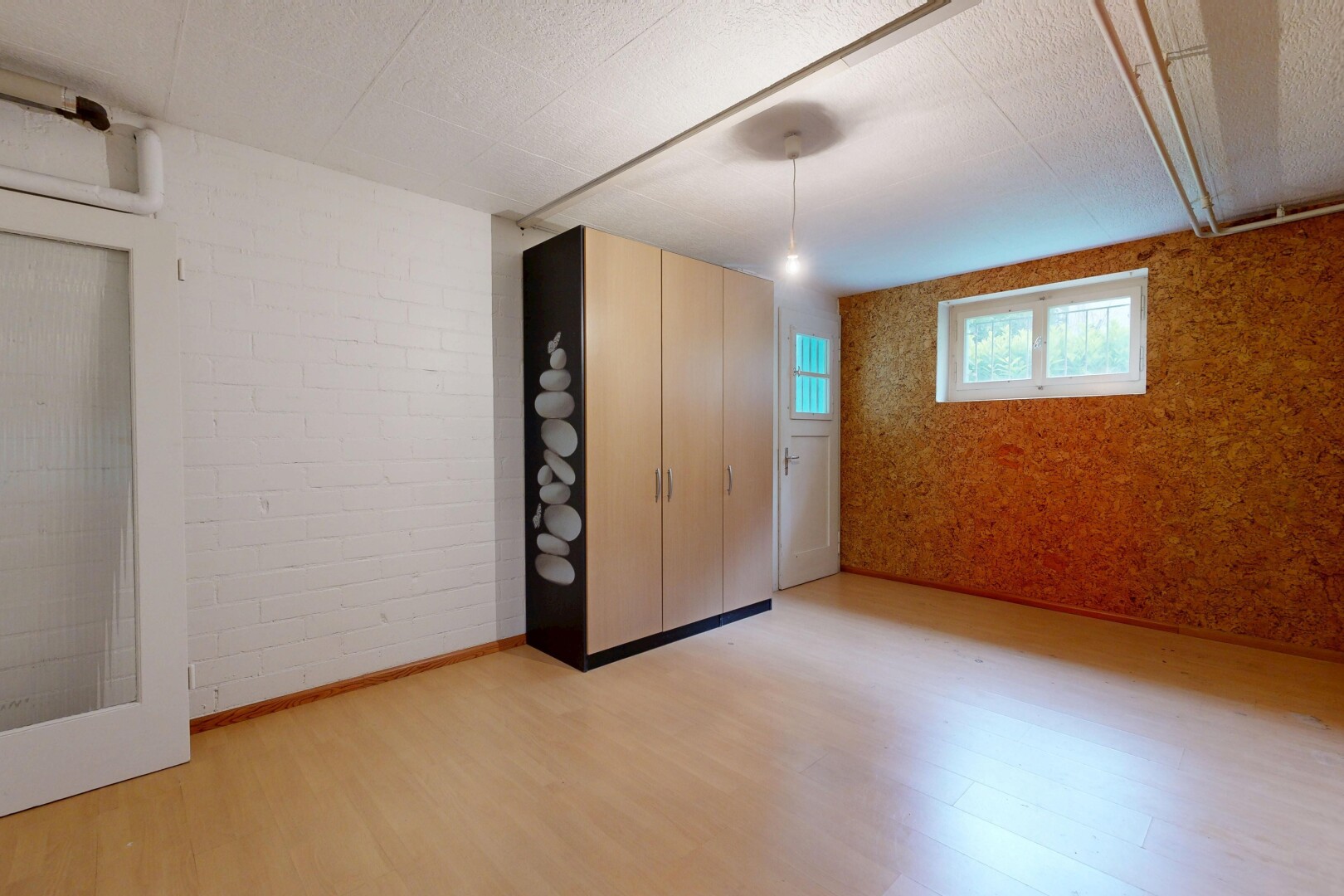 spare room with brick wall, light wood-style floors, a textured ceiling, and an accent wall