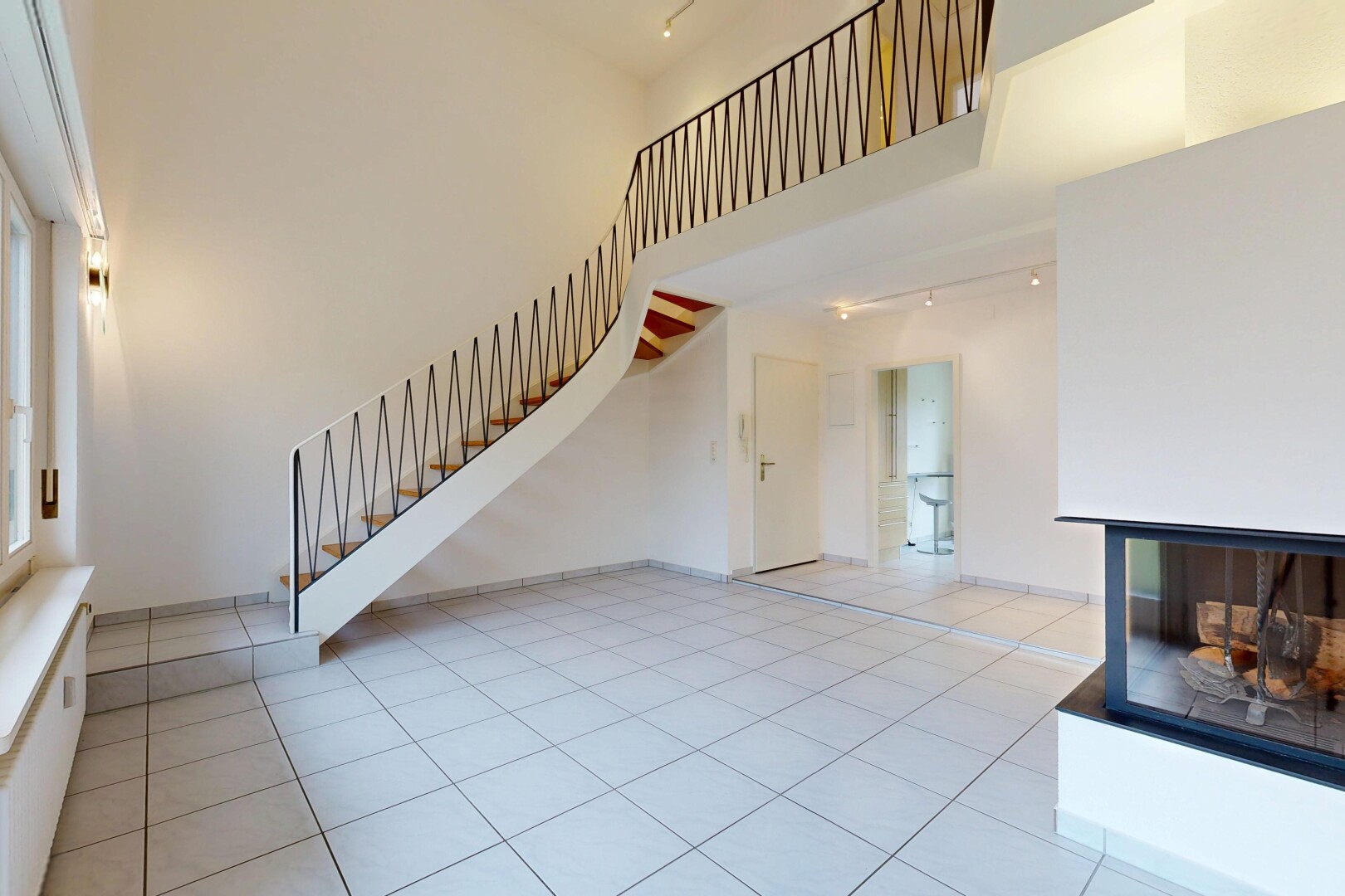 unfurnished living room with a high ceiling, rail lighting, and light tile patterned floors