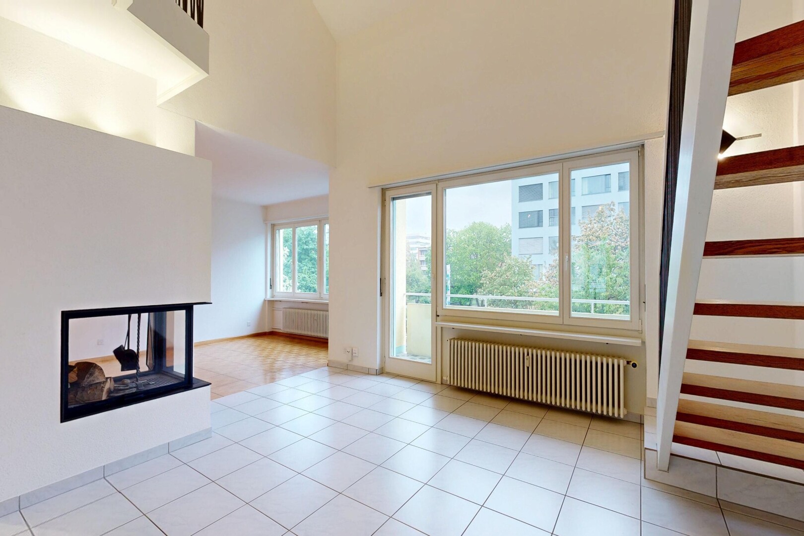 unfurnished living room with a multi sided fireplace, radiator heating unit, a high ceiling, and radiator