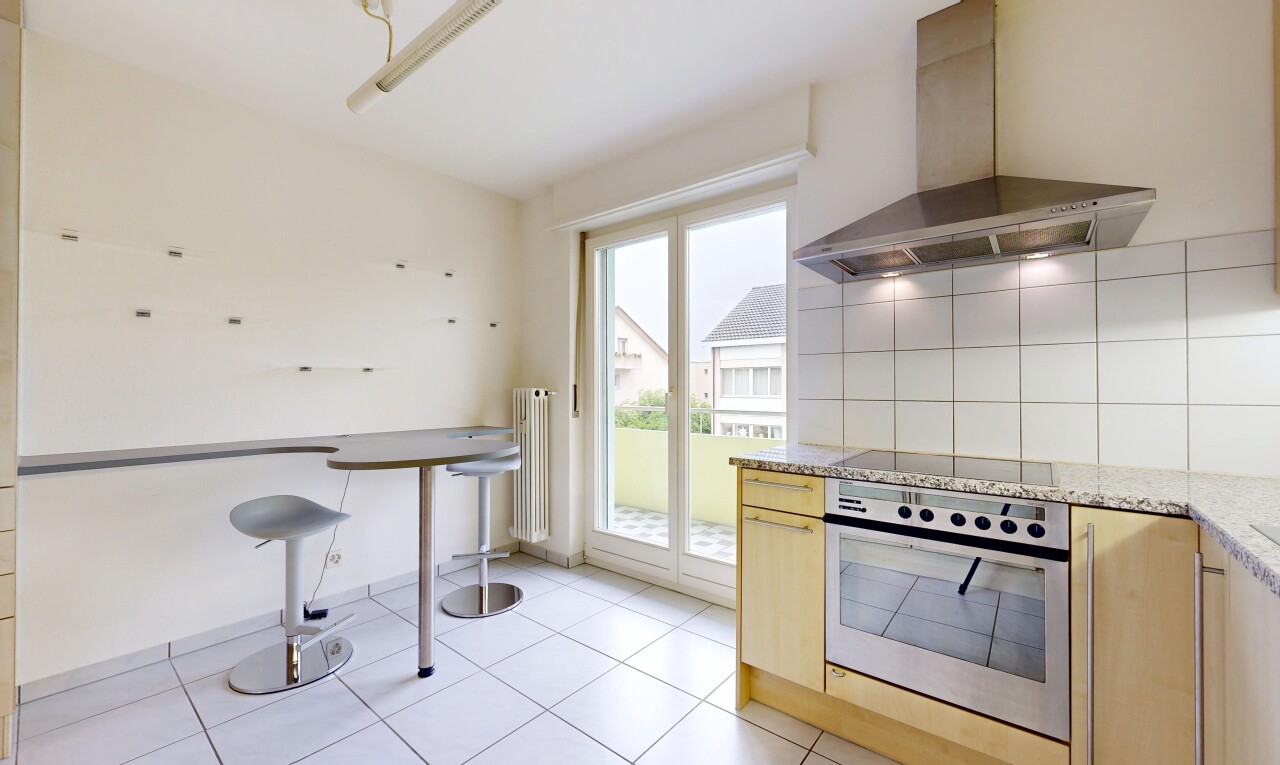 kitchen featuring stainless steel oven, light stone counters, light wood finish cabinetry, and decorative backsplash