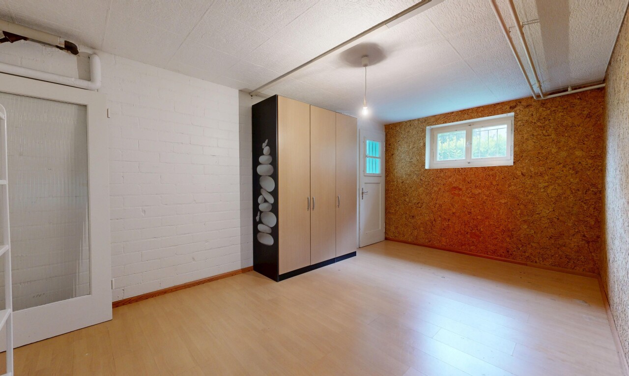 spare room with brick wall, light wood-style floors, a textured ceiling, and an accent wall