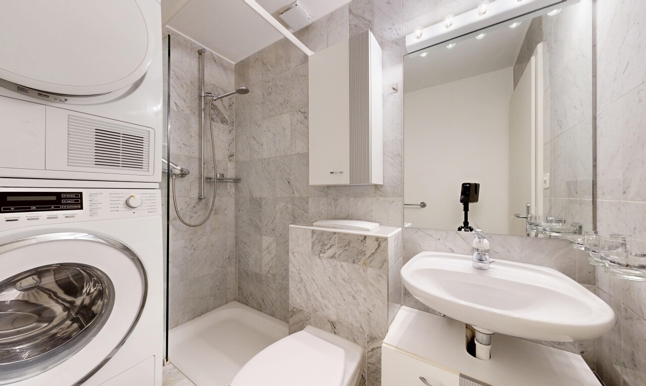 full bathroom featuring a stall shower, tile walls, and stacked washer and clothes dryer