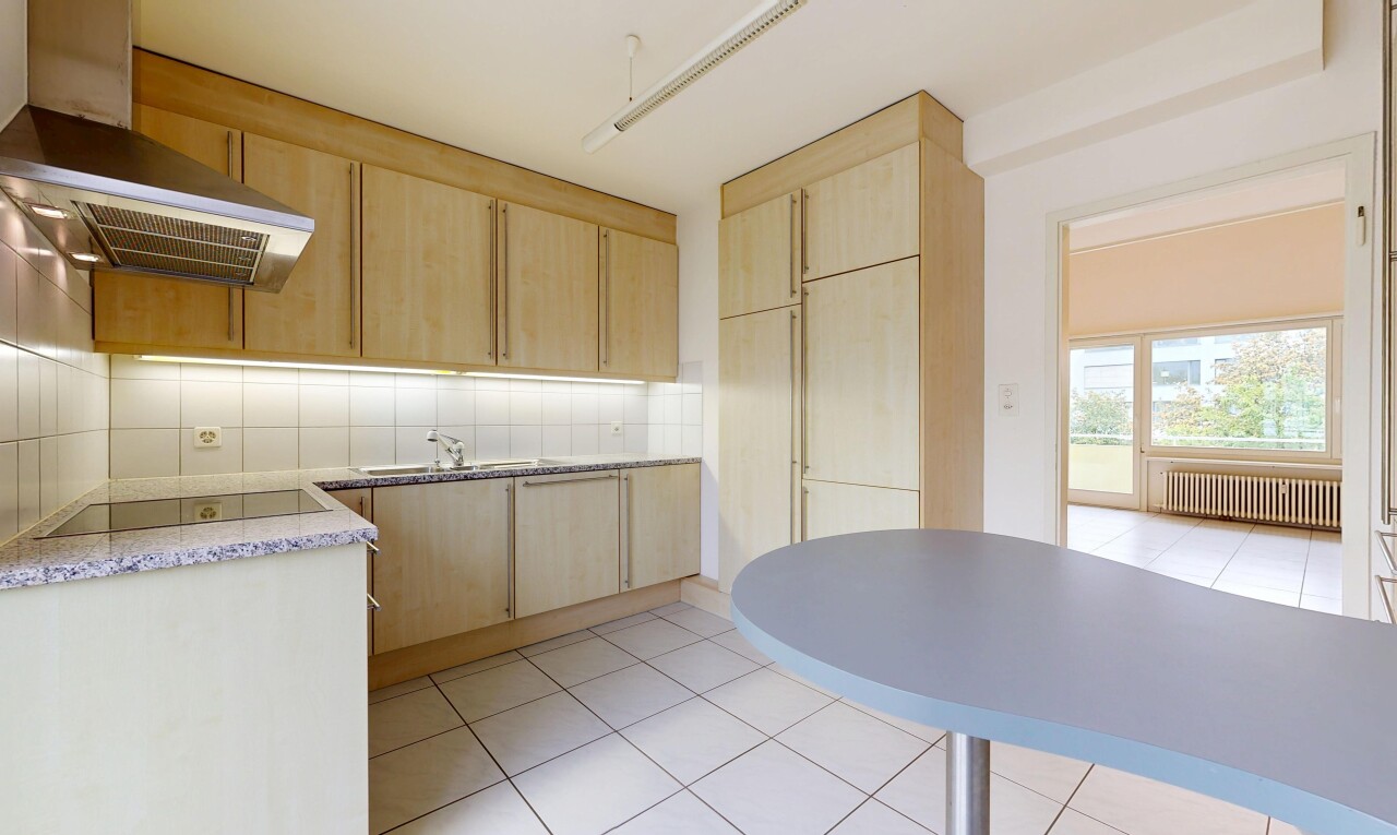 kitchen featuring light wood finish cabinetry, light countertops, radiator, black electric stovetop, and backsplash