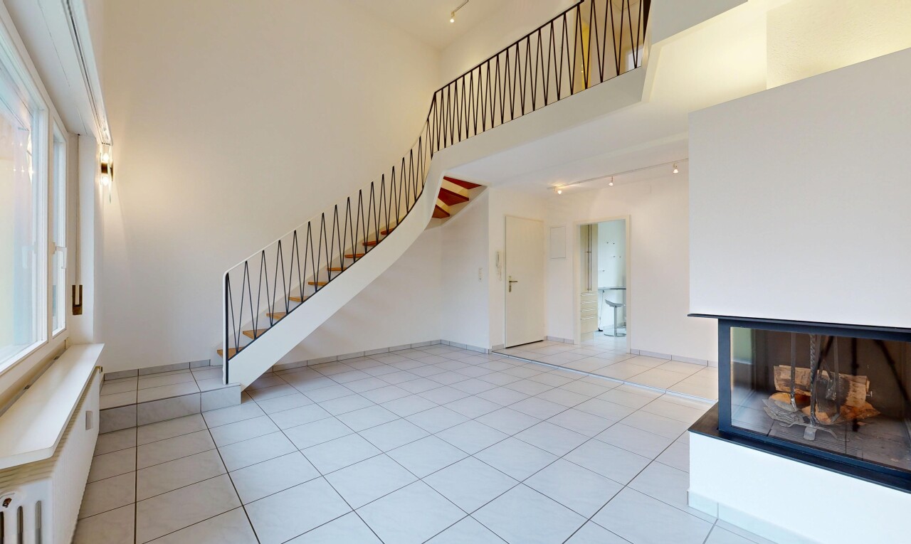unfurnished living room with a high ceiling, rail lighting, and light tile patterned floors