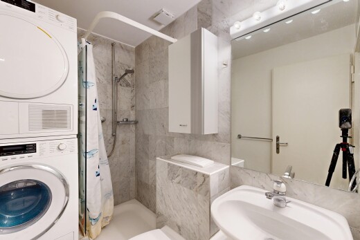bathroom featuring a marble finish shower and stacked washer and clothes dryer