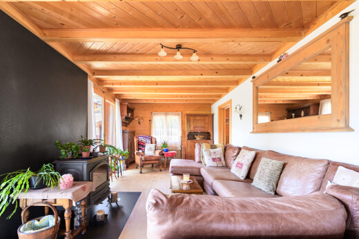salon avec lumière naturelle, natural light, poêle à bois, plafond à poutres, et beamed ceiling
