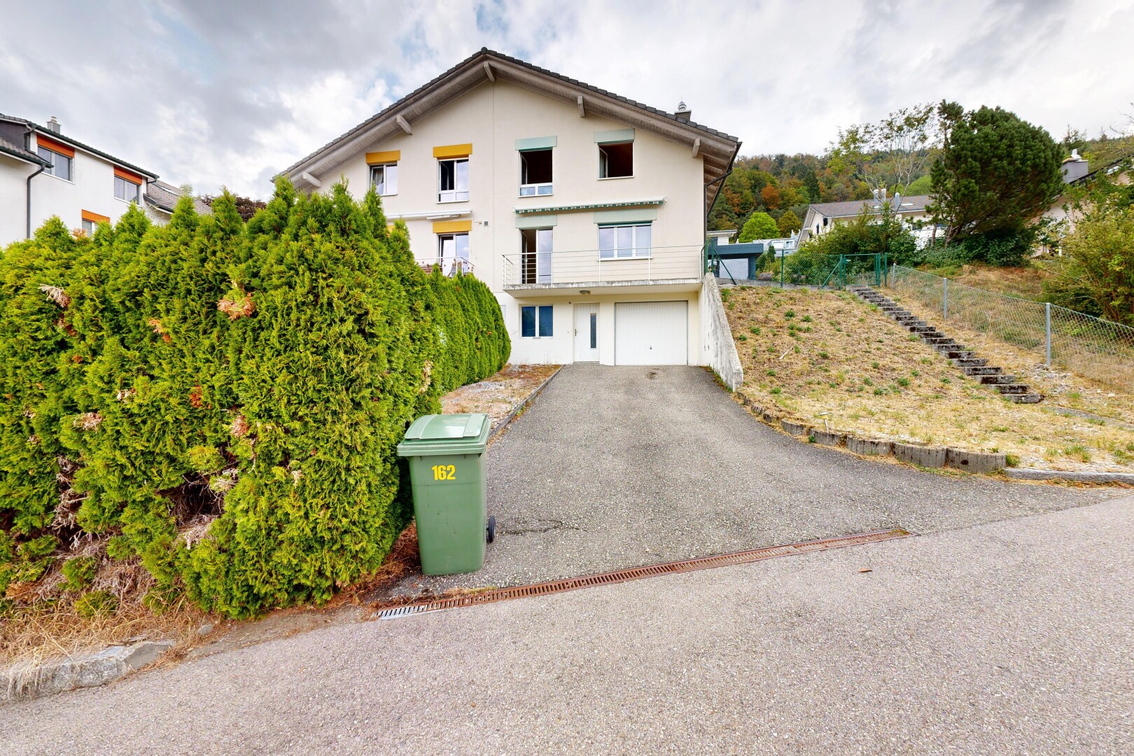 außenansicht mit auffahrt, property visible, eingebaute garage, kellergarage, und stuckverkleidung