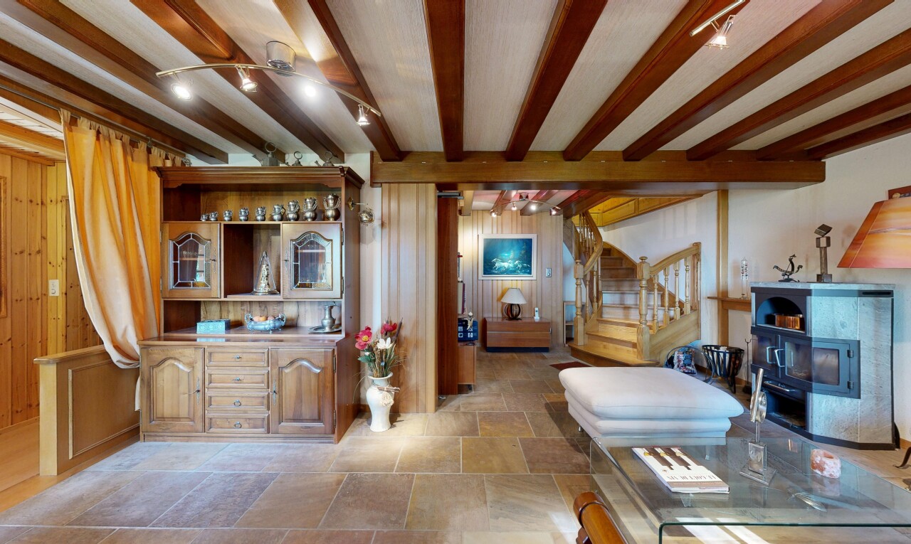 salon avec escaliers, stone finish floor, sol en finition pierre, inside property, et beamed ceiling
