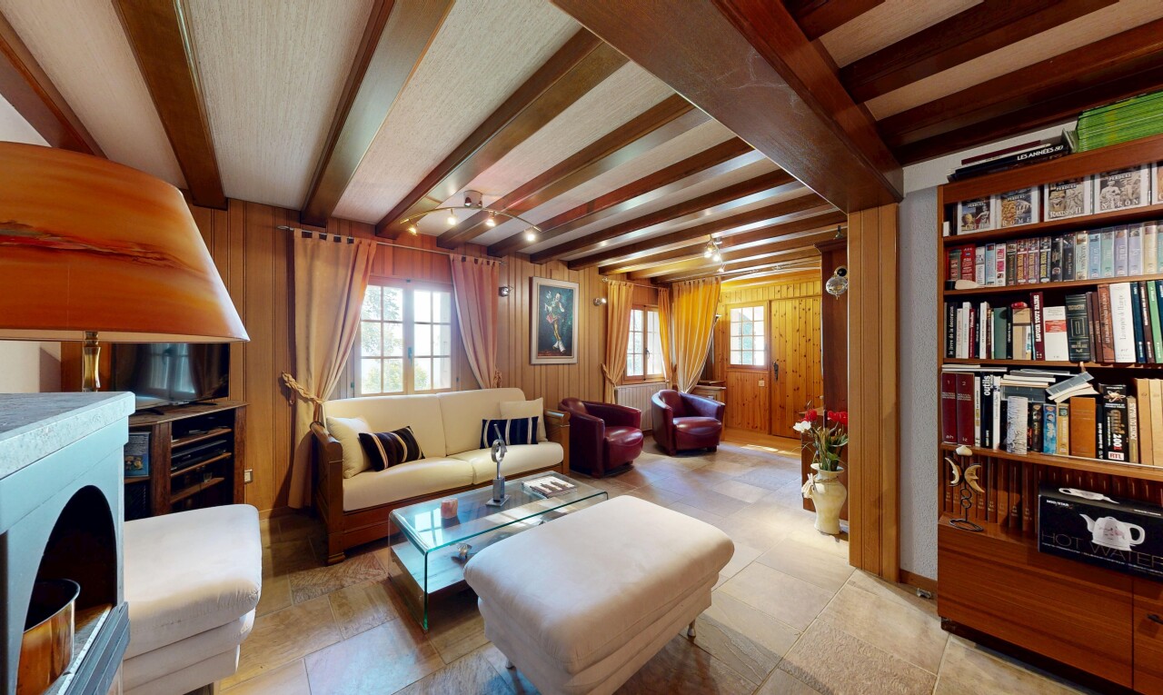 salon avec plafond à poutres, beamed ceiling, inside property, mur en bois, et wood wall