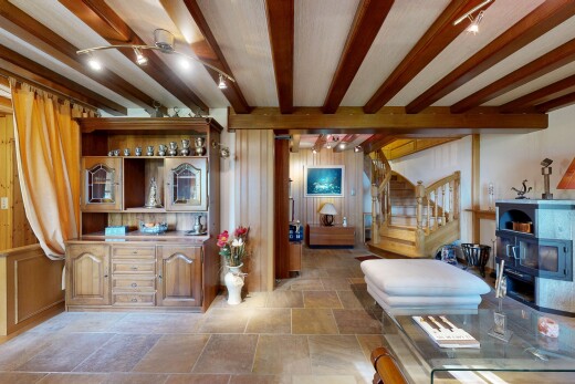 salon avec escaliers, stone finish floor, sol en finition pierre, inside property, et beamed ceiling