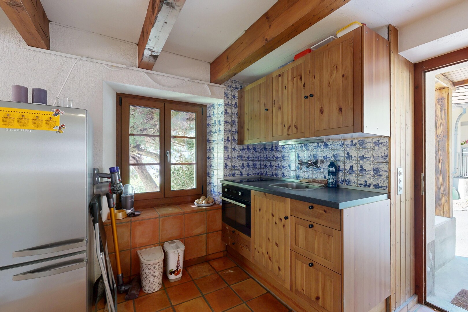 kitchen featuring freestanding refrigerator, oven, dark countertops, tasteful backsplash, and beamed ceiling