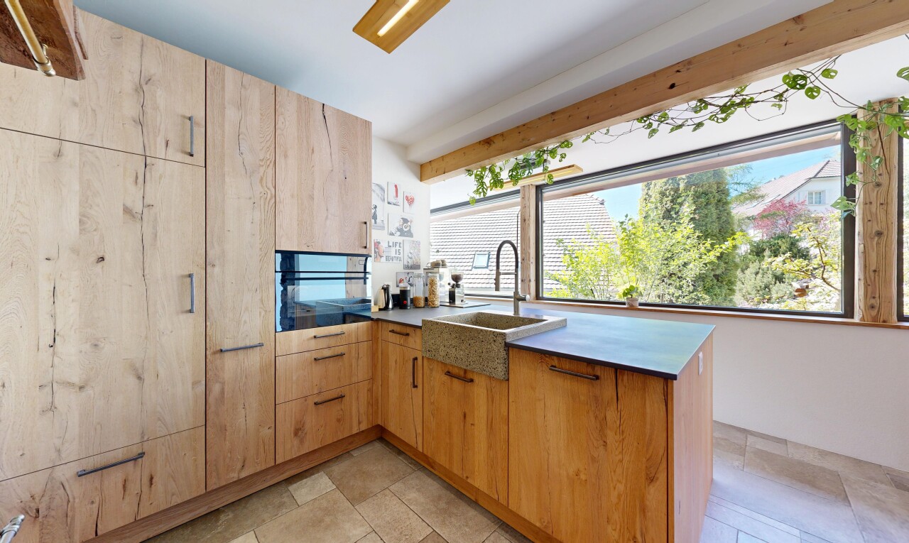 kitchen with a peninsula, black oven, and light wood finish cabinetry