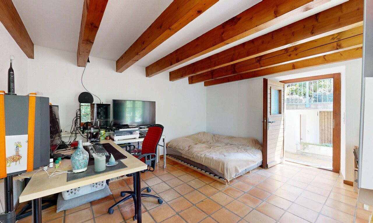 room / bedroom featuring an office area, beam ceiling, and access to exterior