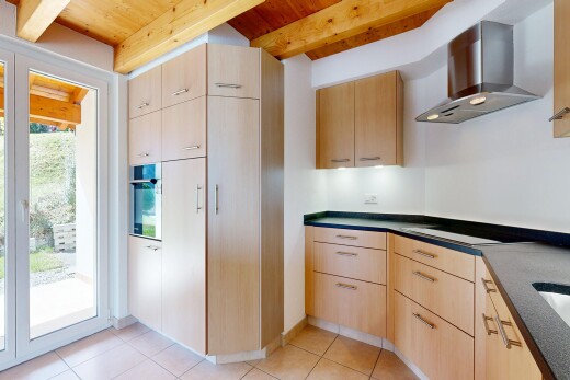 cuisine avec light brown cabinets, armoires marron clair, hotte, dark countertops, et plans de travail