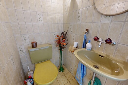 salle de bains avec toilette, évier, miroir, mur en carrelage, et tile wall