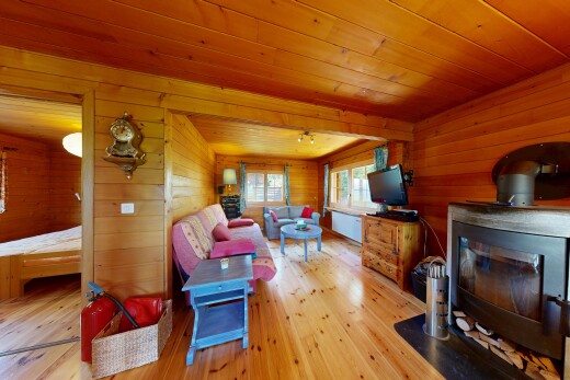 living room with wooden walls, light wood-type flooring, wooden ceiling, and a wood stove