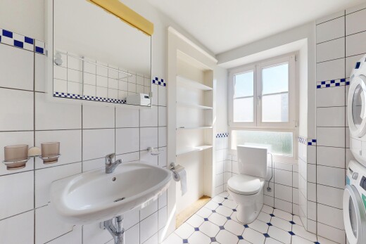 salle de bains avec lave-linge et sèche-linge superposés, tile wall, mur en carrelage, natural light, et lumière naturelle