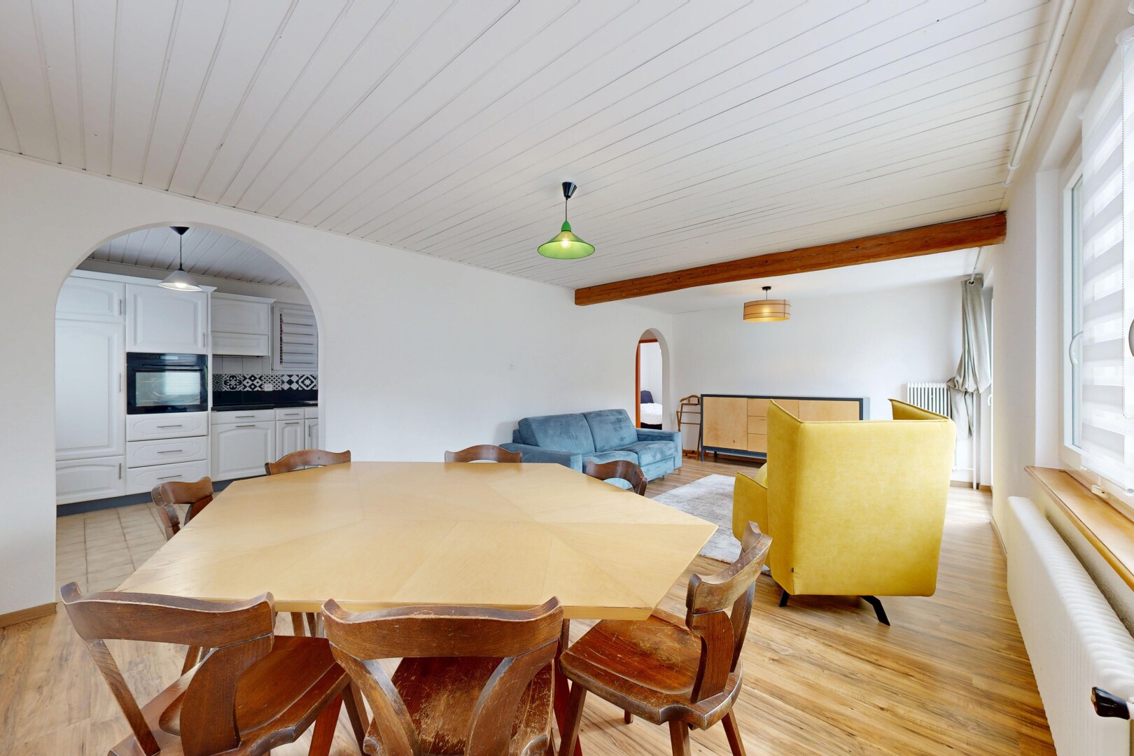 salle à manger avec cloison sèche, lumière naturelle, sol en finition bois, et passages en arc