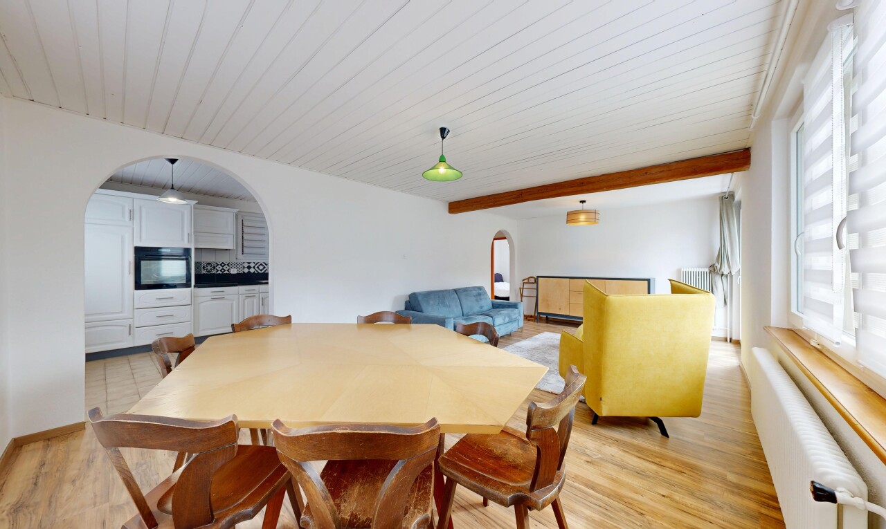 salle à manger avec cloison sèche, lumière naturelle, sol en finition bois, et passages en arc