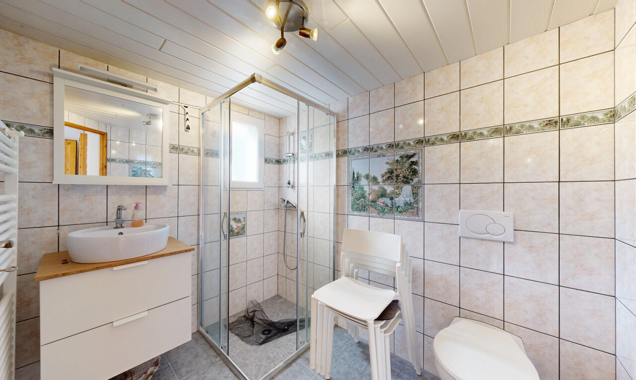 salle de bains avec évier, douche, mur en carrelage, et lavabo (ou coiffeuse selon le contexte)