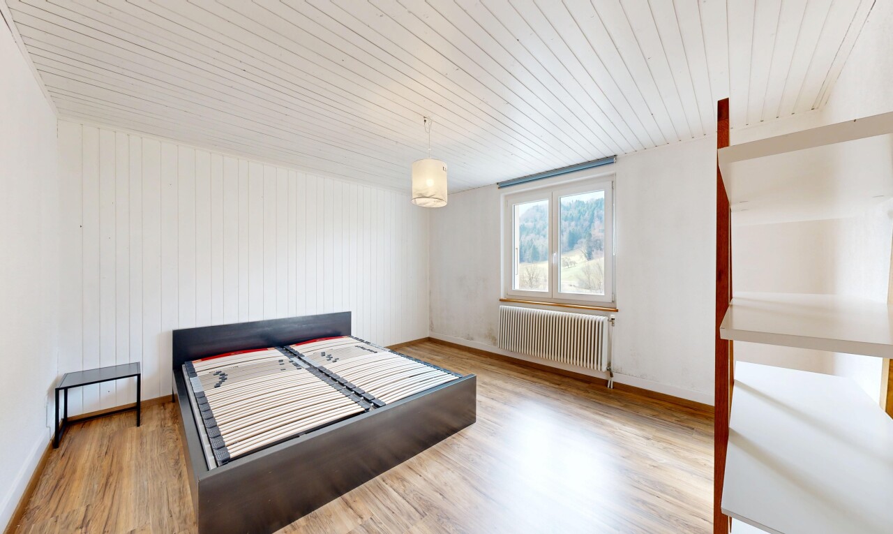 chambre avec radiateur, lumière naturelle, et sol en finition bois