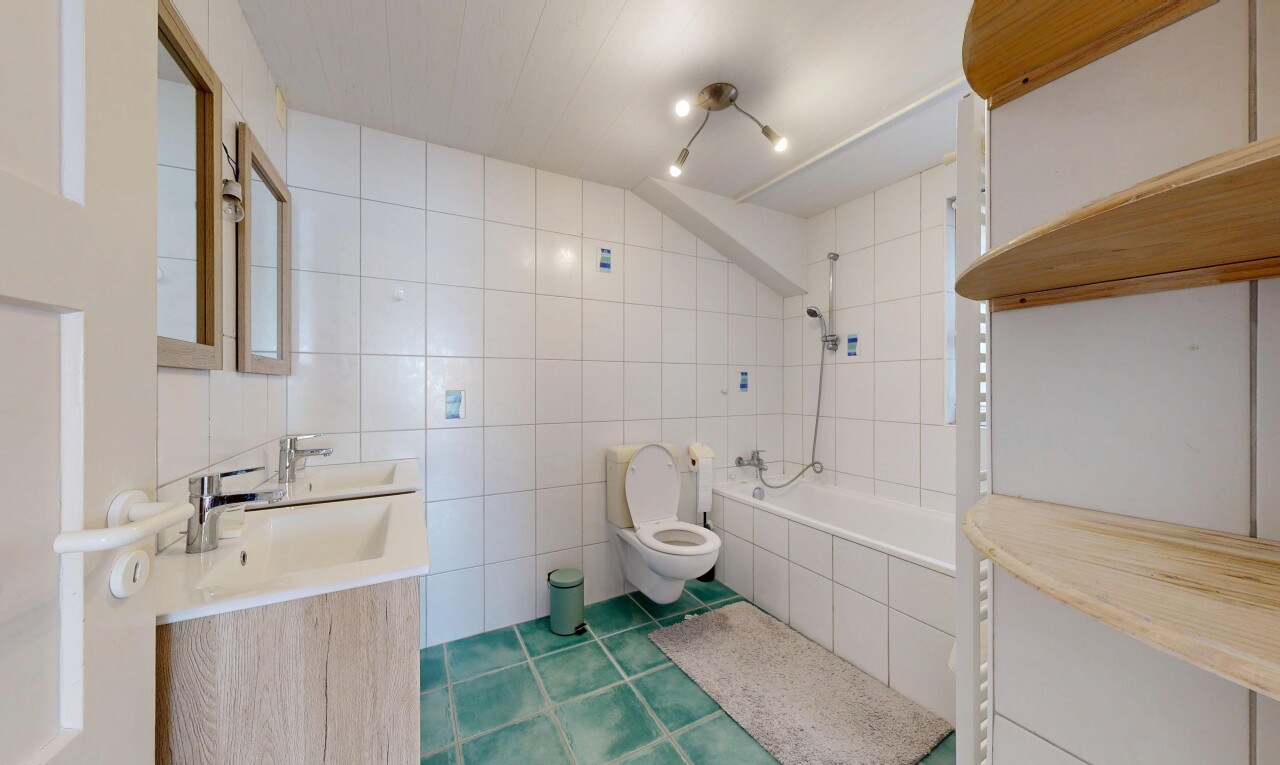 salle de bains avec salle de bain complète, toilette, évier, douche-bain combinés, et mur en carrelage