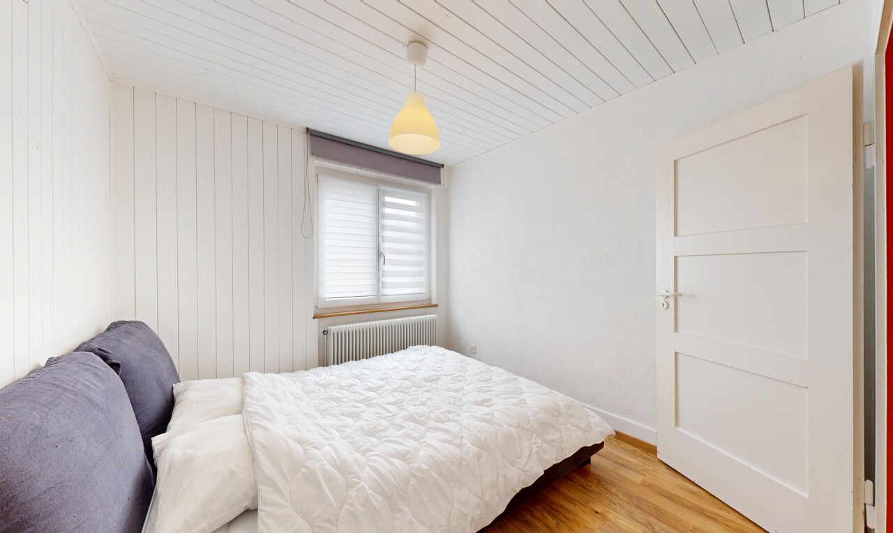 chambre avec cloison sèche, radiateur, lumière naturelle, et sol en finition bois