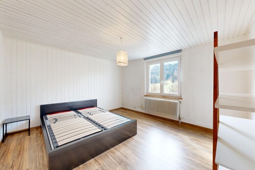 chambre avec radiateur, lumière naturelle, et sol en finition bois