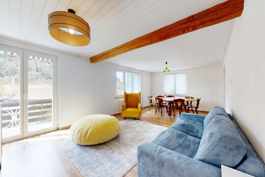 salon / salle à manger avec cloison sèche, lumière naturelle, plafond à poutres, et sol en finition bois