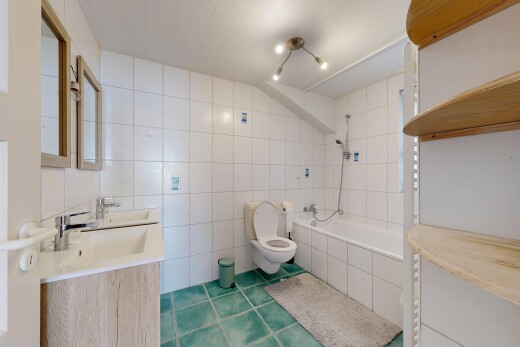 salle de bains avec salle de bain complète, toilette, évier, douche-bain combinés, et mur en carrelage