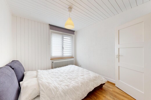 chambre avec cloison sèche, radiateur, lumière naturelle, et sol en finition bois