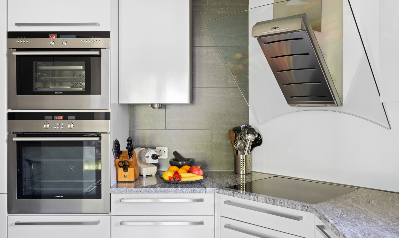 cuisine avec armoires blanches, white cabinets, hotte, four double, et plans de travail en pierre